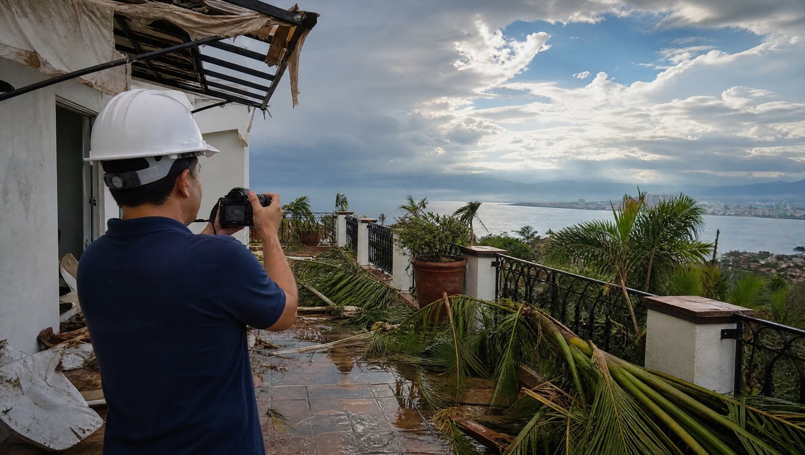Inspector documentando daños de tormenta en una terraza de Puerto Vallarta con palmas caídas durante una inspección de daños por huracán