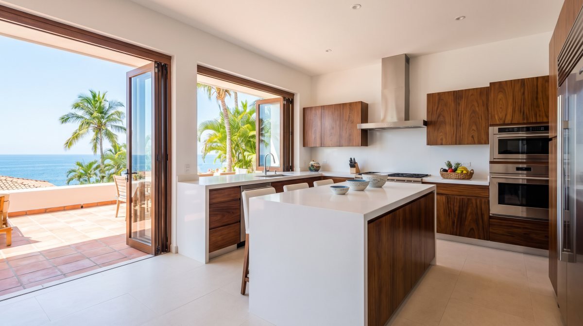 Cocina remodelada con vista al mar en Puerto Vallarta con isla de cuarzo, gabinetes de parota y electrodomésticos de acero inoxidable
